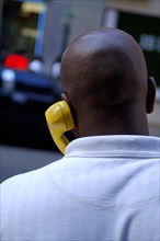 Coloured New Yorker talking on the phone with a yellow handset