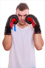 Aggressive determined young male boxer protecting his face with his fists in boxing gloves on his hat on both sides