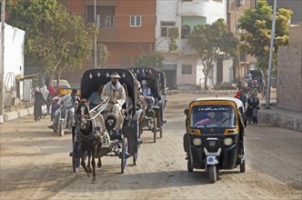 Horse-drawn carriages and a tuk tuk on the main street in Edfu