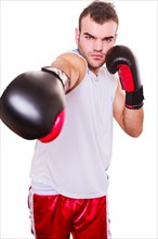 Determined handsome young boxer demonstrates his power with gloved fists in the direction of the camera