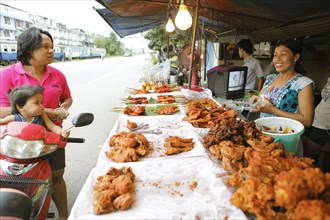 Laughing Thai woman with grilled chicken on a spit
