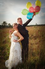 Bridal couple standing on the lawn with balloons