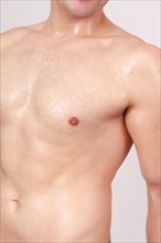 Close up torso view of the left side pectoral muscles and bare chest of a fit young man isolated on grey