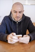Man sitting at the table looking at his mobile phone