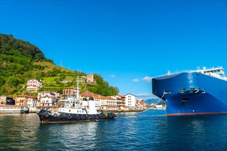 Cargo ship transporting a giant ship in the bay of Pasaia to the open sea Pasajes