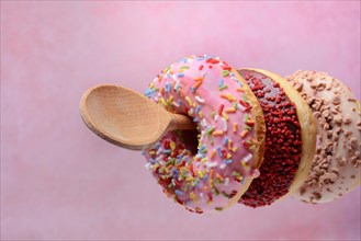Donuts on wooden spoons against a pink background