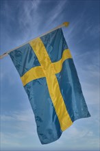 Flag of Sweden against a blue sky with veil clouds