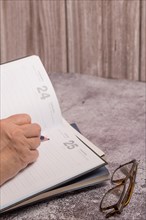 Woman writing in a notebook next to her reading glasses