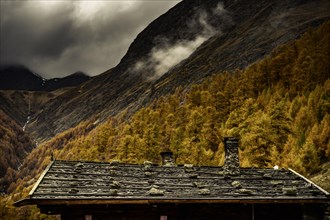 Alpine hut in autumnal mountain landscape with threatening cloudy sky