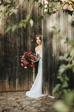 Beautiful bride with a bouquet with wooden door background as a background