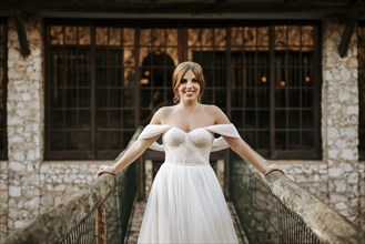 Beautiful bride portrait standing on wooden bridge with stone house behind