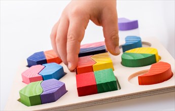 Colorful wooden pieces of a logic puzzle in hand