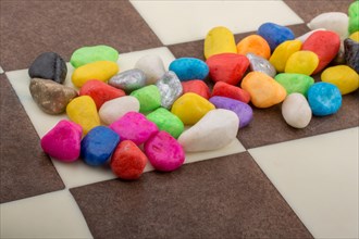 Colorful pebbles spread on checked board background