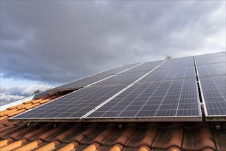 Close-up of photovoltaic system on red tiled roof