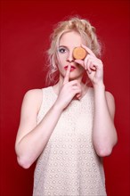 Woman holds a biscuit in front of her eye