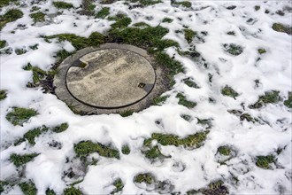 Manhole cover with snow residue