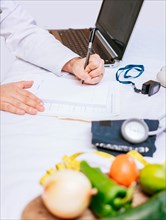 Hands of male nutritionist taking notes at his desk