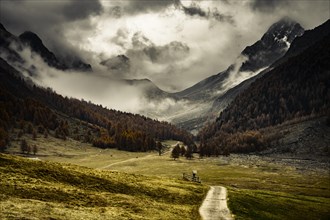 Way cross with path in autumnal mountain landscape with threatening cloudy sky
