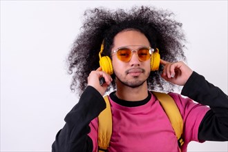 Portrait with pink t-shirt and backpack listening to streaming music. Young man with afro hair on white background