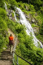 A woman standing on a staircase leading up to the Todtnau waterfall