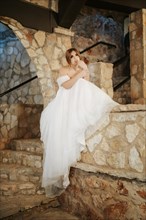 Moody beautiful bride sitting among stone walls