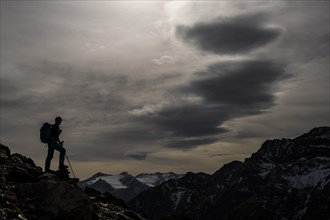Climbers on rocks in backlight with cloudy sky in the background South Tyrolean mountains