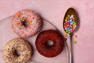 Assorted donuts with icing and spoon with sugar sprinkles