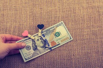 American 100 dollar banknotes with a heart clip on a string