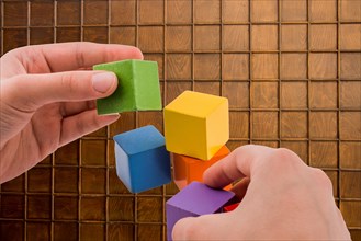 Hand playing with colorful cubes on a background