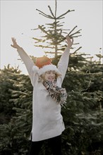 Girl with Christmas hat in front of fir trees