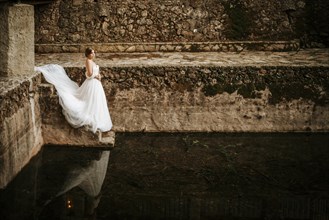Dreamy portraits of a beautiful bride on stone riverbank
