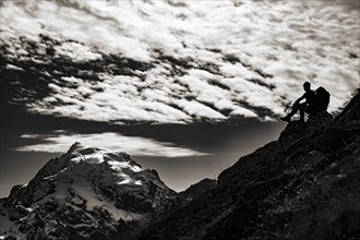 Mountaineer in backlight with cloudy sky in front of Ortler summit massif