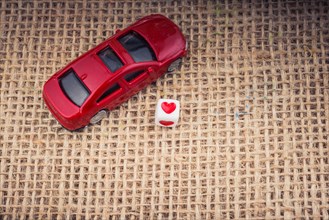 Love cube on a red toy car on a linen canvas