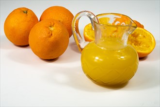 Glass jar with freshly squeezed orange juice and whole oranges at the bottom copy-space
