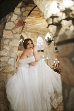 Moody beautiful bride sitting among stone walls