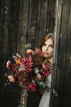 Beautiful bride with a bouquet with wooden door background as a background