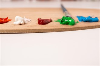 Wooden palette with colored oil paints and brushes isolated on a white background