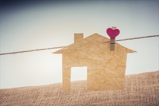 Little paper house attached to a string with a heart clip