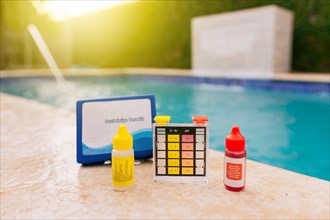 Chlorine test kit on the edge of the pool. PH tester for pool maintenance. Water test kit for swimming pools