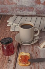 Toasted bread with jam and a cup of coffee on a wooden table