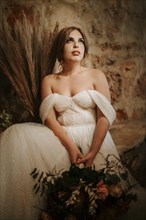 Portrait of beautiful bride with a bouquet in rustic settings