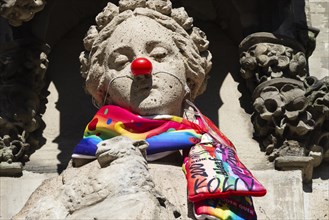 Saint Agnes draped with carnival scarf and red cardboard nose