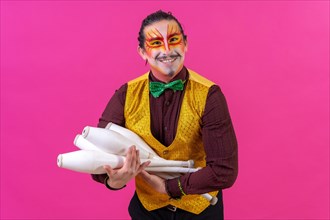 Juggler in a vest and with painted face juggling clubs on a pink background