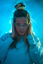 Confident young woman in futuristic glasses gesturing against a blue background