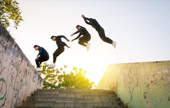 Athlete man doing parkour jumping walls. Low angle of man doing parkour at sunset. Latin guy doing parkour jumping walls.