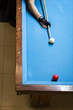 Players arm holding cue above pool table. The player is about to strike the white ball