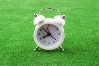 White color alarm clock a on a green grass background