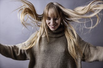 Woman with waving long blonde hair jumps in the air