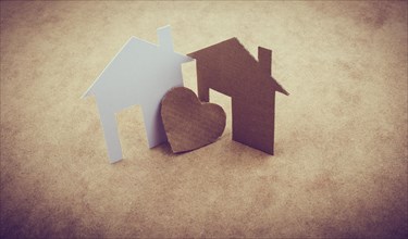 Heart shaped icon and paper houses on a brown background