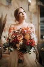 Portrait of beautiful bride with a bouquet in rustic settings